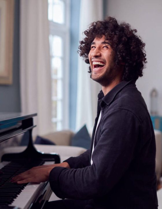 young-man-sitting-at-grand-piano-and-playing-at-ho-2021-08-30-06-14-52-utc