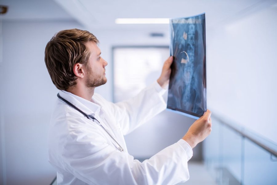 male-doctor-examining-x-ray-in-corridor-2023-11-27-05-07-50-utc