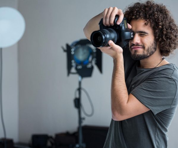 happy-male-photographer-with-digital-camera-in-stu-2021-08-28-17-24-01-utc