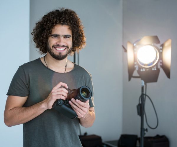 happy-photographer-holding-a-camera-in-the-studio-2021-08-28-17-17-48-utc